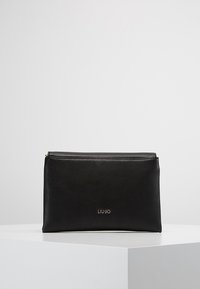 Pochette en cuir noir avec une texture lisse, fermeture éclair et accent logo doré. Forme rectangulaire au design minimaliste.