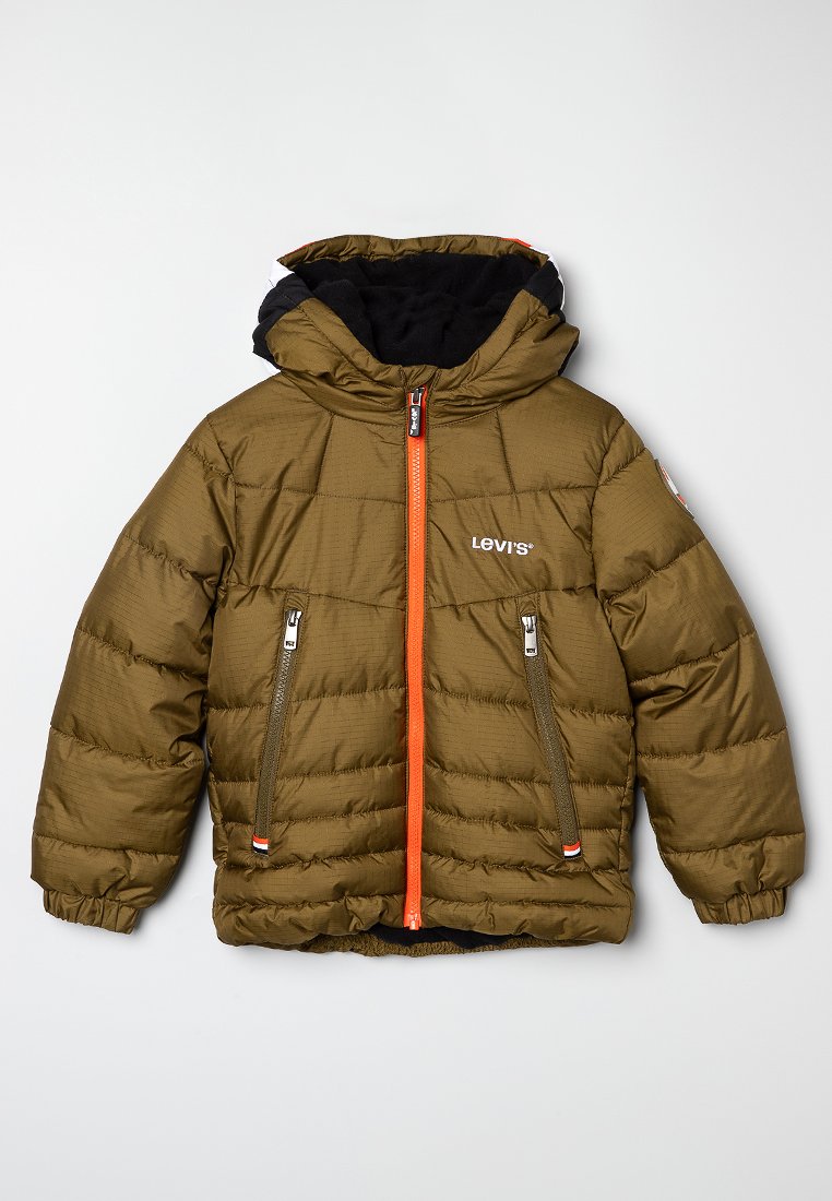 Veste matelassée vert olive avec une capuche doublée en polaire noire, fermeture éclair orange, deux poches zippées et logo sur la poitrine. Détail de couture horizontal.