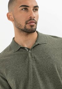 Olijfgroen polo shirt met een gestructureerde afwerking, voorzien van een kraag, een twee-knopen-sluiting en een klein logo op de borst.