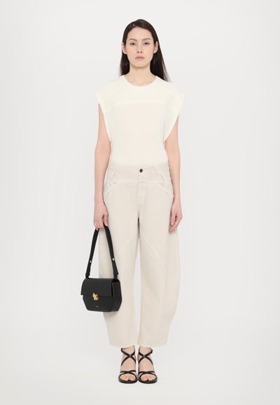 White textured top with short, structured sleeves, paired with light beige wide-leg pants. Black handbag with gold hardware and strappy sandals.