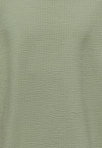 Lysegrønt stof med et tekstureret vaffelvævemønster, der viser små, jævnt fordelte forhøjede firkanter.