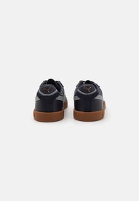 Navy blue leather sneakers with gray accents, gum rubber sole, and gold logo on the heel. Features a low-profile design and rounded toe.