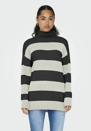 Gestreepte coltrui in donkergrijs en lichtgrijs, met een losse pasvorm en ribgebreide manchetten, gecombineerd met blauwe jeans. Zacht gebreid materiaal.