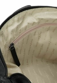 Vista interna di una borsa beige con una fodera caratterizzata da una ripetizione del testo "Harbour 2nd" e una piccola tasca con zip dotata di un tirante nero.