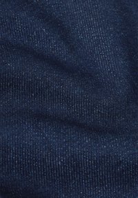 Tummansininen farkkukangas hienolla, teksturoidulla kudonnalla. Siinä on pieniä värieroja ja pehmeä pinta, joka sopii rentoon käyttöön.