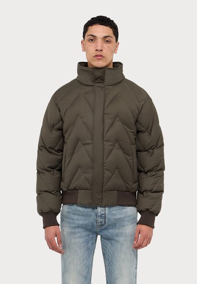 Olívazöld puffajakó, magas gallérral, átlósan tűzött mintával, bordázott mandzsettákkal és aljjal. Elülső cipzáras záródás és minimális dizájn.