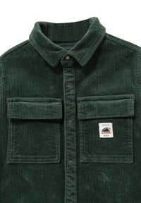 Camicia in corduroy verde scuro con colletto, due tasche anteriori e patch del logo. Tessuto testurizzato con righe verticali e chiusura a bottoni.