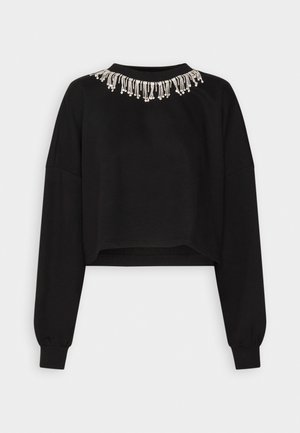 Crewneck negru, scurt, cu mâneci lungi. Prezintă un ciucure decorativ din mărgele argintii în jurul gâtului.