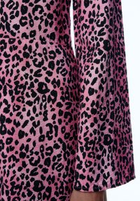 Rosa Stoff mit einem schwarzen Leopardenmuster. Die Textur scheint weich zu sein, mit weiten Ärmeln und einem leichten Glanz.