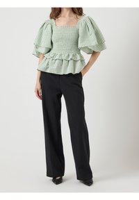 Grön och vit rutmönstrad blus med puffärmar, fyrkantig halsringning och rynkad nederkant, tillsammans med svarta smala byxor.