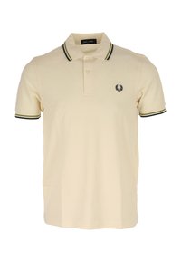 Polo-shirt beige en coton, avec un col classique, trois boutons et un logo sur la poitrine gauche, accompagné d'accents à rayures vert foncé et noires sur les manches.