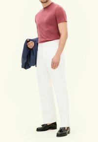 T-shirt fitted bordeaux, pantaloni bianchi su misura, blazer blu marina in mano e mocassini neri con nappine. Tessuto liscio, design elegante.