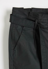 Czarne skórzane spodnie z szerokim pasem w talii, przodem z fałdami oraz bocznymi kieszeniami. Gładka struktura i minimalistyczny krój.