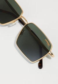 Occhiali da sole quadrati con lenti verde scuro. Sottile montatura in metallo dorato con accenti in tartaruga marrone. Presenta il marchio sulla lente.
