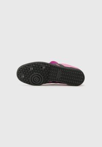 Svart gummisula med texturerat grepp, med en rosa ovandel. Enkel, platt form utan synlig märkning eller hårdvarudetaljer.