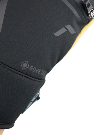 Tejido GORE-TEX negro con un acabado texturizado, que presenta una cremallera oculta y detalles de logotipo impresos, enfatizando un diseño elegante.