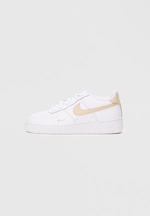 Nike Air Force 1 kedas ar baltu ādas augšdaļu un bēšiem akcentiem, aploksnes purngalu, aizdari ar šņorēm un strukturētu gumijas zoli.