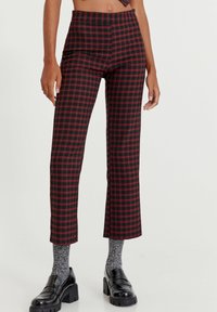 Pantaloni cropped a quadretti neri e rossi con vita alta. Tessuto morbido, taglio dritto, rifiniti con una cintura spessa. Abbinati a scarpe chunky.