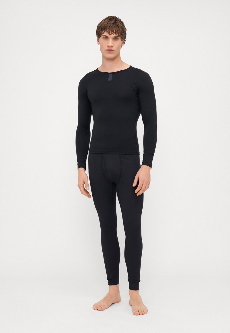 Black long-sleeve top and fitted leggings made of stretch fabric. The top features a round neckline and a small tag at the chest.