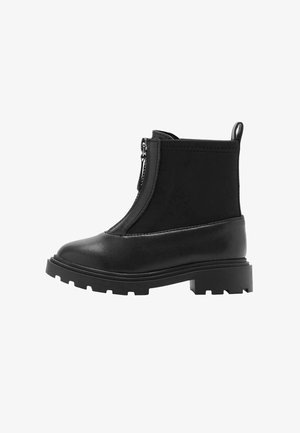 Bottine noire à la cheville avec semelle épaisse, fermeture éclair à l'avant, bout lisse, languette à l'arrière et détails cousus sur les côtés supérieurs.