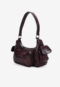 Bolso de mano de imitación cuero burdeos con un diseño curvado, bolsillo con cremallera y correa de hombro ajustable. Presenta dos detalles laterales con solapa.