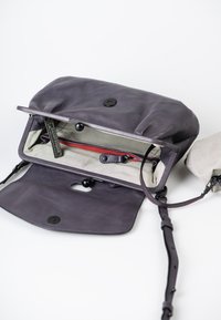 Borsa a tracolla in pelle viola con pattina pieghevole, dotata di chiusura a bottone, foderata a righe e con una tasca con zip rossa all'interno.