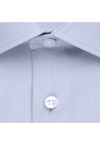 Ljusblå skjortkrage med en enstaka vit knapp och synliga texturdetaljer. Närbild visar fin sömnad och tygmönster.