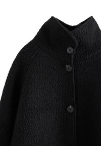 Svart fleecejacka med hög krage, strukturerad yta och fyra framknappar. Designen är sömlös med raglansärmar.