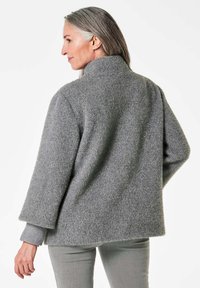 Grau gestrickte Jacke mit hohem Kragen, gerippter Textur und weiten Ärmeln. Verfügt über eine lockere Passform und besteht aus weichem, warmem Material.