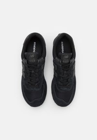 Schwarze Mesh- und Wildledersneaker mit dicken schwarzen Schnürsenkeln, gepolstertem Schaft und dem charakteristischen "N"-Logo an den Seiten. Klassisches Modell 574.