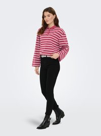 Haut à manches longues de style polo avec des rayures roses et blanches. Associé à un jean skinny noir et des bottines noires avec une boucle décorative.
