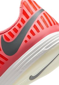 Sporta apavi ar rozā augšdaļu un sarkaniem akcentiem, elpojoša tīkla dizains un izteikts pelēks Nike swoosh. Balta Lunarlon zole.