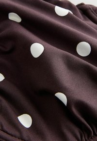 Pruun kangas valgete täppidega, sile tekstuur, kogutud servad ja peen kuma. Omab ümaraid, ühtlaselt paiknevaid mustreid.