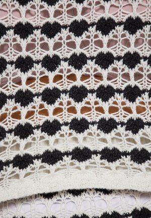 Textil din dantelă cu modele circulare alternative în alb și negru, cu detalii intricate de lucru deschis și o finisare moale, texturată.