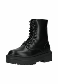 Bota de combate negra de cuero con cordones, suela gruesa con tacos y caña hasta el tobillo, con ojales metálicos y detalle de marca en el talón.