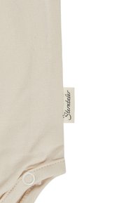 Beige fabric with sewn-in label reading "Sterntaler" and a white snap button on the edge of a garment.
