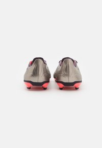 Scarpette da calcio con finitura grigio metallico, suole nere e accenti rosa. Presentano un design elegante con una forma ergonomica e un tacco pronunciato.