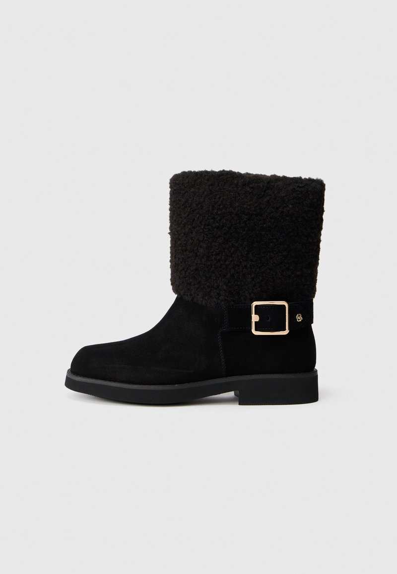 Botine negre din suede, cu un mansetă de blană texturată și pufoasă, de culoare neagră, și o cataramă din metal aurit pe lateral. Talpă plată.