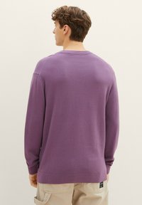 Maglione viola a maglia con un motivo testurizzato, maniche lunghe, polsini e orlo a coste. Presenta un piccolo etichetta di marca sul lato inferiore.