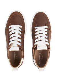 Sneaker in pelle marrone con lacci bianchi e un dettaglio bianco sul tallone. Presenta una punta arrotondata e una texture cucita.