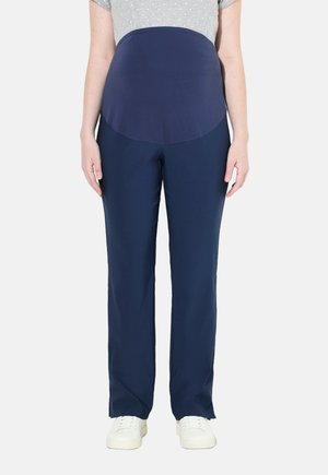 Pantalones de maternidad navy con panel suave para la barriga, diseño de pierna recta y cinturilla elástica; combinados con una blusa gris claro con lunares y zapatillas blancas.