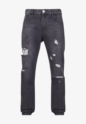 Dunkelgraue Jeans aus Denim mit mehreren beschädigten Löchern und ausgefransten Kanten; klassisches Fünf-Taschen-Design mit Knopfverschluss und Gürtelschlaufen.