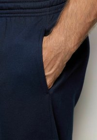 Pantalones jogger azul marino con un bolsillo lateral; la tela parece suave y lisa, con una cinturilla elástica y un ajuste relajado.