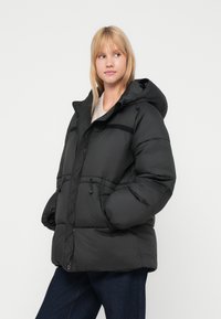 Black puffer jacket with a hood, featuring a zip front, elastic cuffs, and side pockets. Made from quilted, water-resistant material.