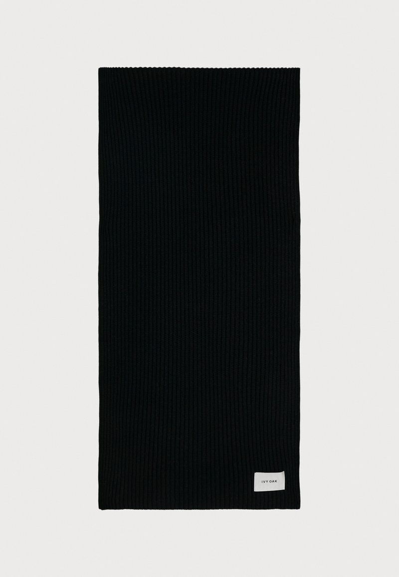 Cachecol preto canelado feito de um tecido macio, com uma pequena etiqueta branca com o nome da marca numa das extremidades. Forma retangular e design texturizado.