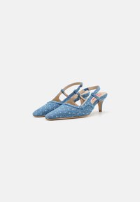 Blue denim slingback heels with pointed toes, a low heel, cross straps, and a textured fabric featuring a faded finish.