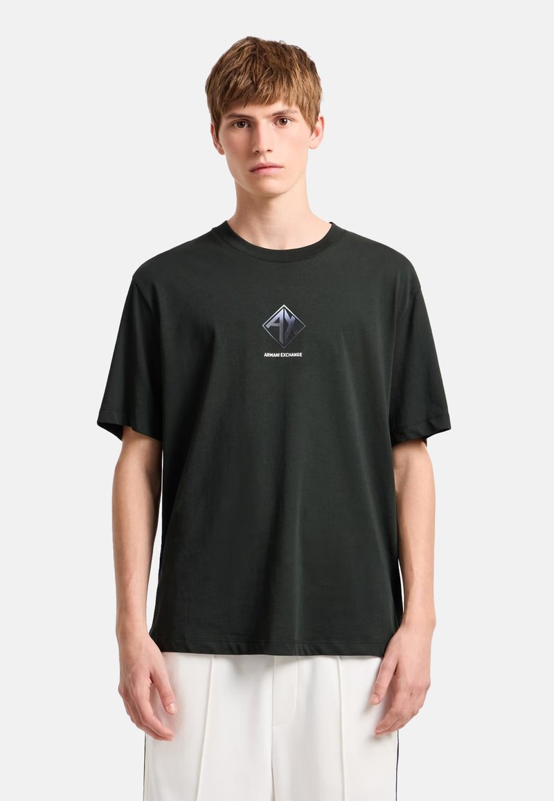 Camiseta negra de algodón con un logotipo metálico en forma de diamante en el pecho y mangas cortas. Diseño clásico de cuello redondo.