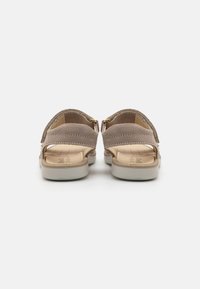 Beige semskede sandaler med åpen bak, to frontstropper og en polstret innersåle; har såle i hvit gummi og minimal sømdetalj.