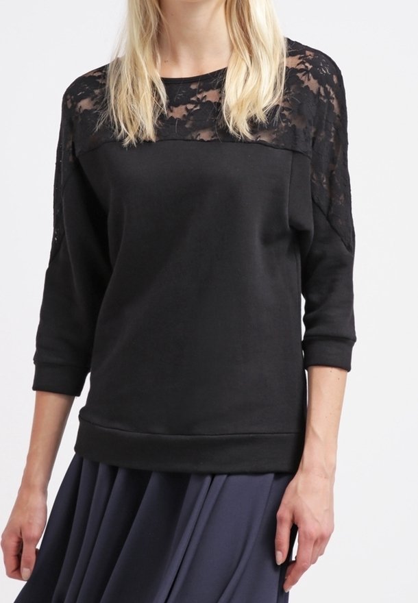 Sweat-shirt noir avec détail en dentelle sur les épaules, manches trois-quarts et encolure ronde. Tissu doux avec une coupe décontractée.