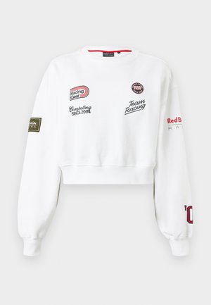 Valge lühendatud dressipluus võidusõudeteemaliste plaastrite ja tekstiga, sealhulgas "Racing Gear", "Team Racing" ja "Red Bull Racing" varrukatel ja rinnal.